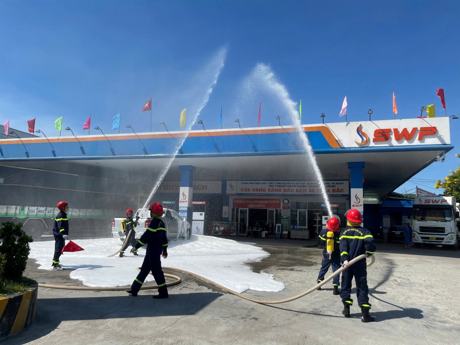 Các chiến sĩ và nhân viên phối hợp phun bọt foam, xử lý tình huống cháy giả định tại khu vực trạm xăng.