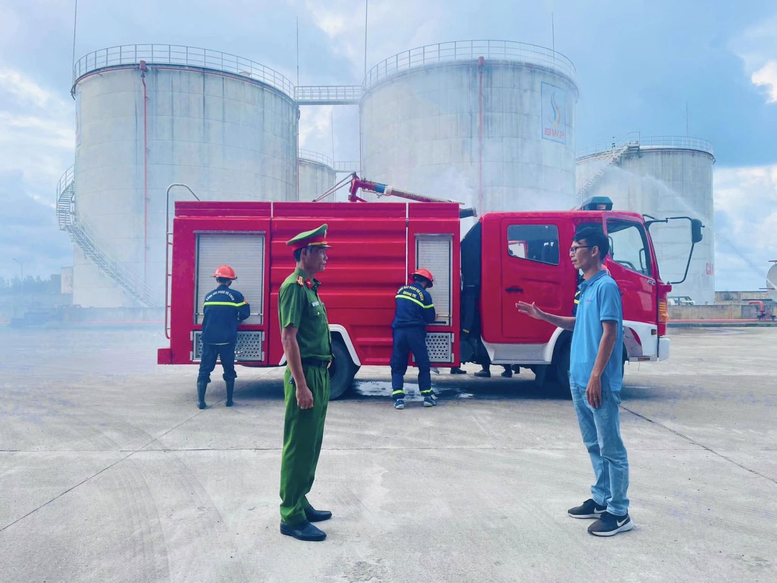 Cán bộ Phòng Cảnh sát PCCC & CNCH cùng đại diện Tây Nam S.W.P trao đổi phương án trước khi diễn tập, xe chữa cháy được chuẩn bị sẵn sàng tại khu vực bồn chứa xăng dầu.
