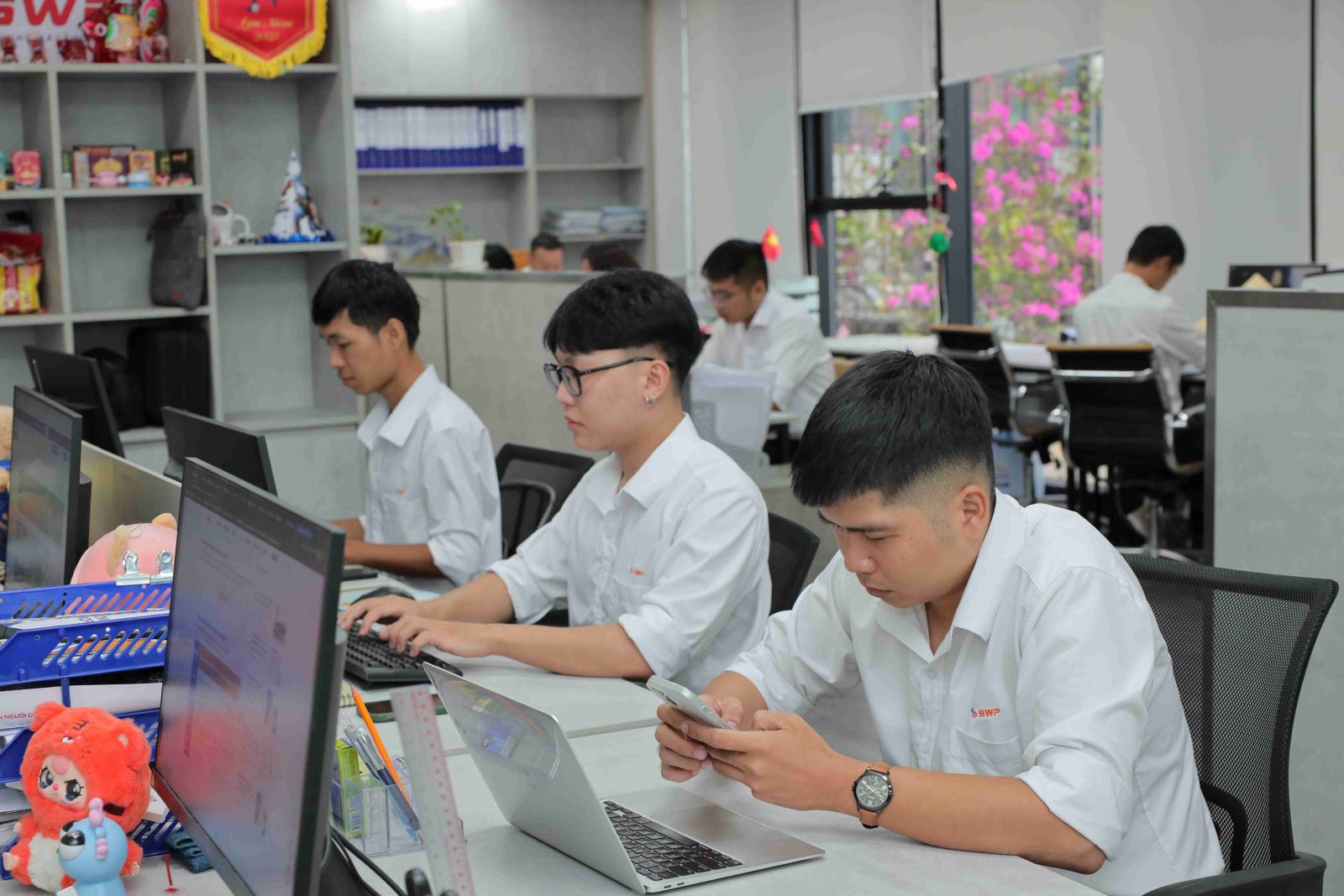 Đội ngũ nhân viên văn phòng Tây Nam SWP làm việc tại máy tính trong môi trường hiện đại, hỗ trợ vận hành và kinh doanh hệ thống cửa hàng xăng dầu.